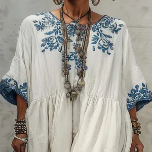 Detailed view of the bohemian white dress with blue floral print, crew neck and sleeves.