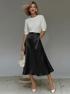 Close-up detail showcasing smooth satin texture and elegant drape of black midi skirt.