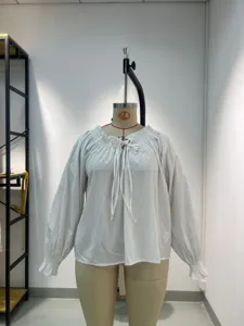 Detailed view of the white long sleeve blouse with tie neck and ruffled cuffs in studio.