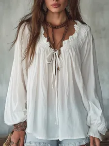 Detailed view of white long sleeve blouse, V-neck with string ties and delicate ruffled collar.