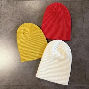 Detailansicht von einfarbigen Winter-Strickmützen in Rot, Gelb und Weiß, Rippstrick-Design.
