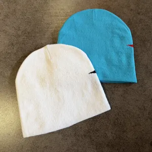 Gestrickte Beanie Mütze Detailansicht, stylische warme Freizeitmütze in weißer und blauer Farbe.