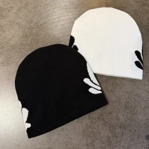 Close-up detail of stylish knit beanie hats in black and white with floral jacquard design.