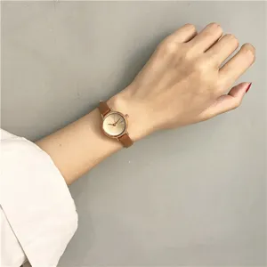 Close-up detail van een minimalistisch quartz horloge met bruine lederen band om de pols.