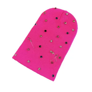 Modieuze felroze gebreide muts versierd met kleurrijke strass-steentjes en veiligheidsspelden.