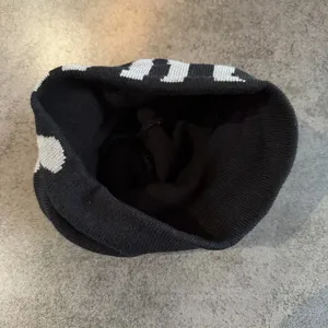 Close-up of the black and white knitted beanie, showing stylish woven text and soft texture.
