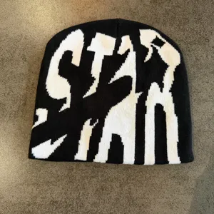 Detailed view of the black and white knitted beanie featuring bold streetwear typography.