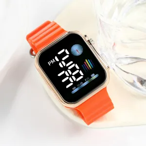 Close-up detail of the orange silicone strap and rose gold square digital watch screen.