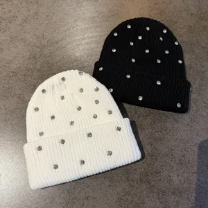 Detailed shot of winter warm knit beanies decorated with sparkling rhinestones in black and white.