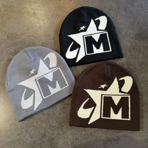 Detalle de gorro de punto suave, diseño exclusivo con estrella y letra M para abrigar en invierno.