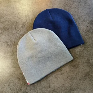 Detailopname van gezellige gebreide mutsen in grijs en blauw met zachte stofstructuur.