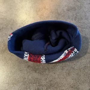 Gedetailleerd overzicht van warme gebreide muts met klassieke rood-wit-blauwe jacquardpatronen.