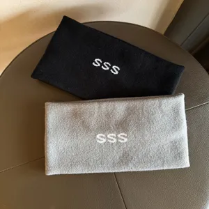 Detailed shot of thick knitted winter headbands in black and grey with white SSS embroidery.