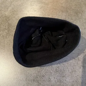 Vue détaillée d'un bonnet en tricot noir avec motif d'éclair blanc, style streetwear tendance.