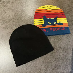 Détail du bonnet en tricot montrant la texture du chat rayé noir et la matière douce.