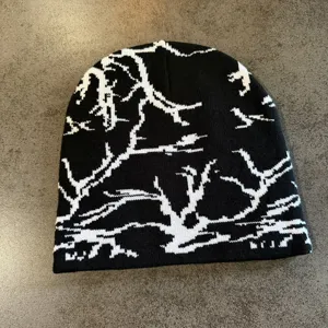 Détail du bonnet en tricot noir et blanc, présentant un motif jacquard abstrait branches et éclairs.