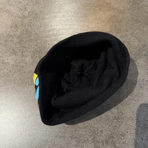 Gros plan du bonnet en tricot noir avec motif chat, bonnet d'hiver chaud et doux detail.