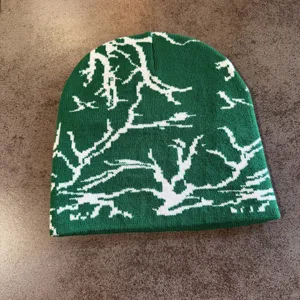 Gros plan sur le bonnet en tricot vert avec motif jacquard abstrait blanc style streetwear.