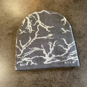 Bonnet en tricot gris détail, motif d'arbre blanc, style streetwear chaud en gros plan.