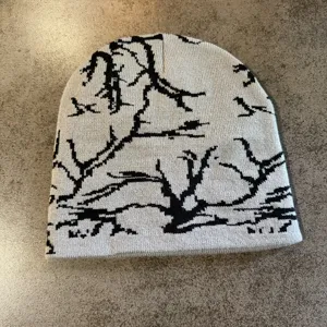 Vue détaillée d'un bonnet en tricot gris avec motif d'arbres noirs style urbain hiver