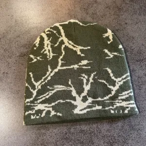 Détail en gros plan d'un bonnet en tricot vert avec un motif de camouflage de branches.