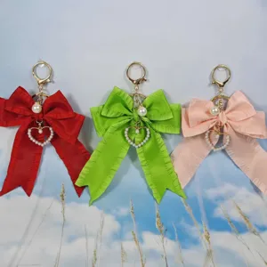 Pleated ribbon bow keychain with pearl heart pendant, stylish bag charm for women.