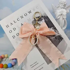 Detailed view of the pink pleated ribbon bow keychain featuring a pearl heart pendant for bags.