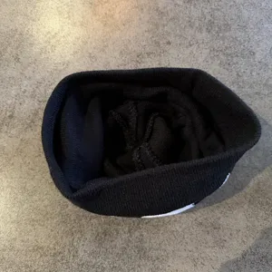 Black knit beanie detail view showing interior texture and warm wool fabric construction