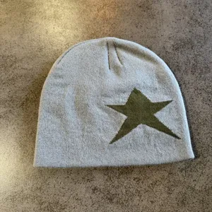 Grey knitted star beanie detail shot, autumn winter warm pullover hat texture showcase.