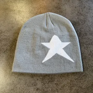 Close-up detail of gray knit beanie featuring a bold white star pattern for winter warmth.