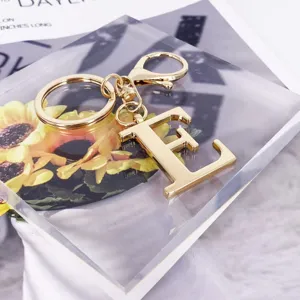 Close-up detail of a gold-colored uppercase letter E keychain on a clear acrylic block.