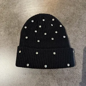 Black knit beanie hat with sparkling rhinestones, warm winter fashion streetwear stylish cap.