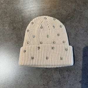 Detailed shot of a beige knit beanie decorated with sparkling rhinestones for warm daily wear.