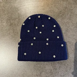 Rhinestone knit beanie detail shot, dark blue winter warm cap with sparkling crystals.