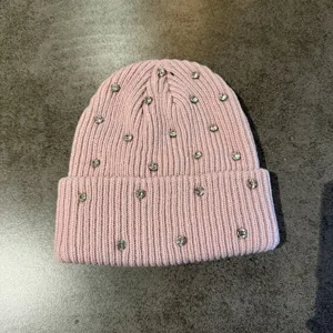 Detailed close-up of pink knitted beanie embellished with sparkling rhinestones, cozy texture.
