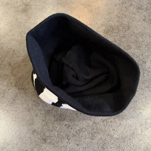 Black white knit beanie hat detail view, stylish winter warm pullover cap for street style.