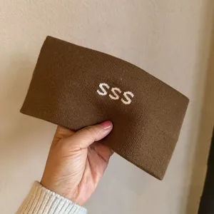 Detailed view of the brown knitted headband featuring white SSS letter knit design and texture.