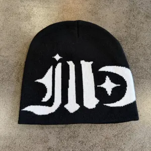 Detailed view of black and white knit beanie featuring gothic style typography and star moon graphics.