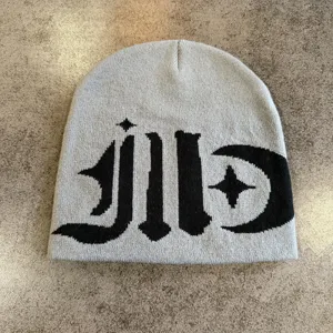Grey knitted beanie hat with stylish gothic lettering and star moon pattern for winter warmth.