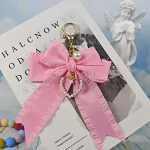 Close up of a cute pink pleated ribbon bow keychain with pearl heart charm and metal clasp.