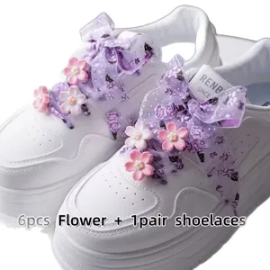 White platform sneakers with purple sheer organza ribbon shoelaces and pink flower charms.