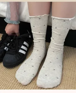 Gros plan de chaussettes mi-mollet pour femmes à pois et bord ondulé, tricot beige.