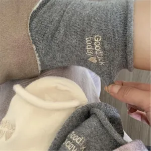 Close-up view of cozy thick cashmere socks featuring cute embroidery and soft roll cuff.