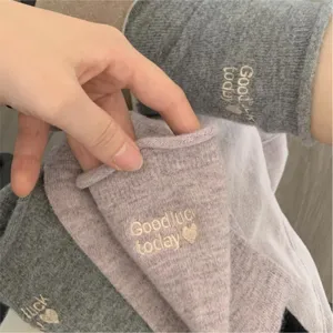Close-up detail of soft cashmere blend socks featuring embroidered letter patterns and rolled cuffs.