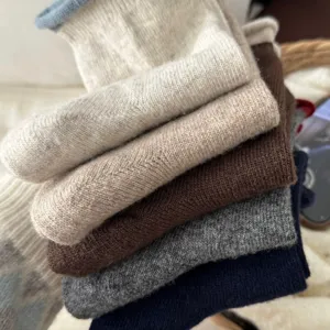 Primo piano di morbide calze in lana accoglienti in colori neutri, trama lavorata a maglia.