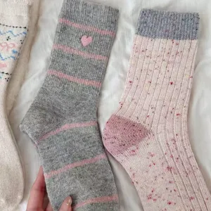 Calcetines de lana grises y rosas acogedores con bordado de corazón y textura suave.