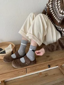 Close-up detail of gray ribbed crew socks with white stripes and cute black bow. Perfect style.