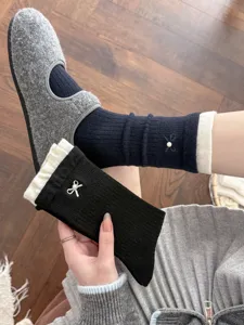 Close-up detail of women's cashmere socks featuring contrast ribbed cuffs and pearls.