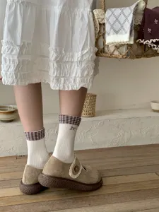 Detail view of women's mid-tube socks with plaid cuff and cute bow, cozy autumn winter style.