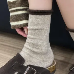 Dettaglio di calze a metà altezza in maglia calda da donna con risvolto marrone invernale.